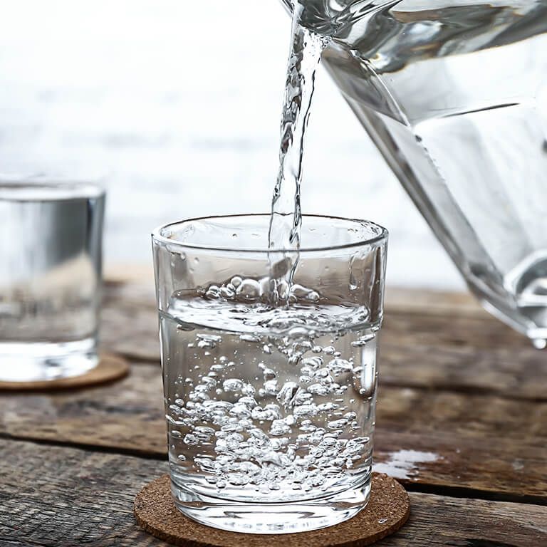 Ein Glas Wasser wird eingeschenkt: Harnsteine entfernen funktioniert bei kleinen Ablagerung auch über den Urin.  